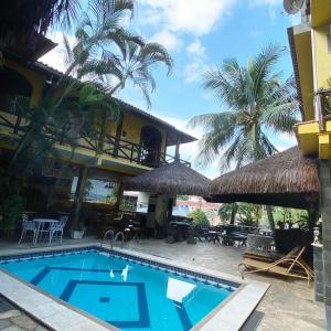 una piscina di fronte a una casa con palme di Morada do Aventureiro ad Angra dos Reis