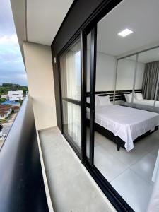 een slaapkamer met een bed op een balkon bij MaxLoft - Apto novo Smart Tv, lavanderia in Joinville