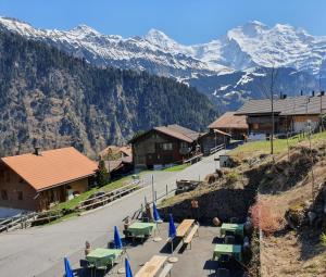 a group of tables and chairs with mountains in the background at Hotel Restaurant Waldrand, Isenfluh in Isenfluh