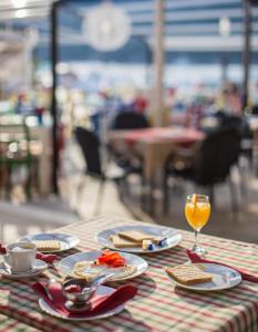 una mesa con platos de comida y un vaso de zumo de naranja en Seafront rooms Koluna, en Komiža