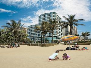 um grupo de crianças brincando na areia na praia em Blue Waters Hotel em Durban