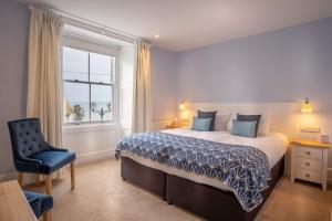 una camera con un letto e una sedia e una finestra di Marazion Hotel a Marazion