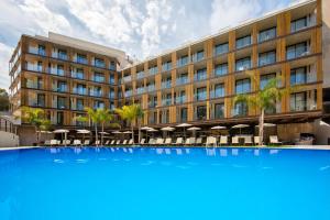 un grand bâtiment avec une grande piscine bleue en face dans l'établissement Golden Costa Salou - Adults Only 4* Sup, à Salou