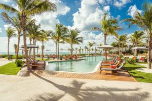 einen Pool in einem Resort mit Stühlen und Palmen in der Unterkunft Andaz Mayakoba All Inclusive in Playa del Carmen