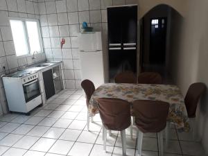 uma cozinha com mesa e cadeiras e uma cozinha com frigorífico em Casas em Condomínio próximo da praia com 2 dormitórios, churrasqueira e 3 vagas de garagem em Ubatuba