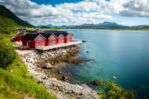 una fila di case rosse sulla riva di un lago di Lofoten Rorbu Lodge a Offersøya