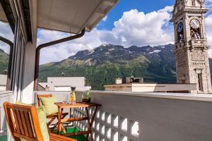 un balcón con una torre del reloj, una mesa y sillas en Hotel Arte en St. Moritz