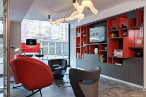 a living room with red and black chairs and a tv at iQ Hotel Milano in Milan