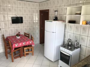 cocina con mesa y nevera blanca en Pousada Mera en Florianópolis