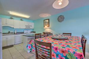 Orange Beach Resort Condo with Pool - Walk to Beach! في شاطئ أورانج: مطبخ وغرفة طعام مع طاولة مع نمط زهرة