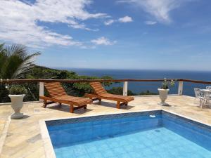 een patio met 2 stoelen en een zwembad bij Casa das Ilhas in Ilhabela