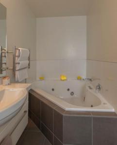 a white bathroom with a tub and a sink at Airport Palms Motel in Christchurch