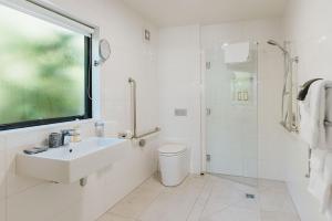 La salle de bains blanche est pourvue d'un lavabo et d'une douche. dans l'établissement Rimu Lodge, à Hokitika