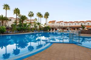 una piscina en un complejo con palmeras y edificios en Wyndham Residences Golf del Sur, en San Miguel de Abona