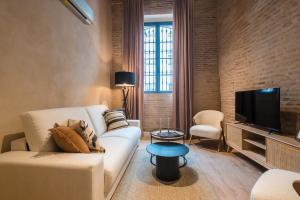 sala de estar con sofá blanco y TV en La Sillería de Triana by Magno Apartments en Sevilla