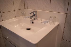 un lavabo blanco en un baño con dos vasos. en Hotel Monika en Zutendaal