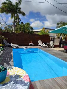 una piscina azul con sillas y sombrilla en An Ti Kaz La en Sainte-Anne