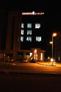 a building with a sign on the side of it at night at Nizwa Inn - نزوى إن in Nizwa