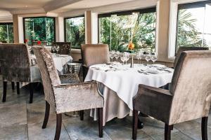 a dining room with tables and chairs and windows at The View Boutique Hotel & Spa in Amanzimtoti