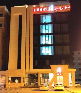 a building with two cars parked in front of it at Nizwa Inn - نزوى إن in Nizwa