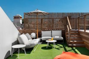 un patio con sillas y mesas blancas y una sombrilla en Lazy Days - Adults Only - Duna Parque Resorts & Hotels, en Vila Nova de Milfontes