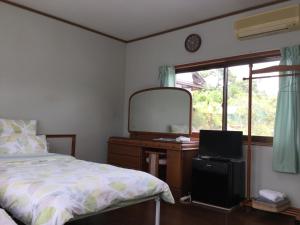 ein Schlafzimmer mit einem Bett und eine Kommode mit einem Spiegel in der Unterkunft Guesthouse Yui in Hongu