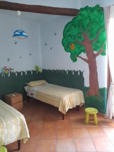 Habitación con 2 camas y un árbol pintado en la pared. en Casa Mandarino Forio Ischia en Isquia