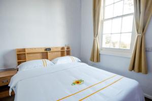 Cama blanca en habitación con ventana en Hearty Center Motel, en Katoomba