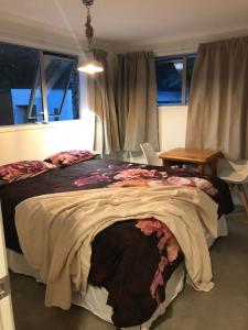 a bedroom with a bed and a table and windows at Almost Heaven BNB in New Plymouth