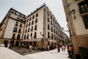 um grupo de pessoas andando em uma rua com edifícios em Hotel Atari em San Sebastián