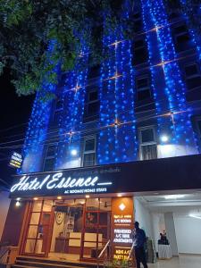 a man standing in front of a building with blue lights at Hotel ESSENCE in Vellore