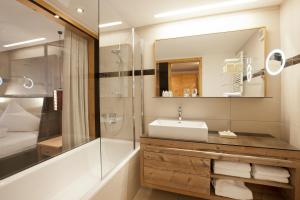 a bathroom with a sink and a shower and a mirror at Hotel Walliserstube in Damuls