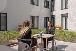 duas mulheres sentadas numa mesa em frente a um edifício em Citybox Antwerp em Antuérpia