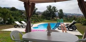 einen Tisch und Stühle neben einem Pool in der Unterkunft Quinta de Carvalhal - Casa de Campo in Guimarães