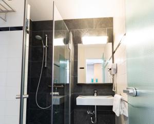 a bathroom with a shower and a sink and a mirror at Bastion Hotel Groningen in Groningen