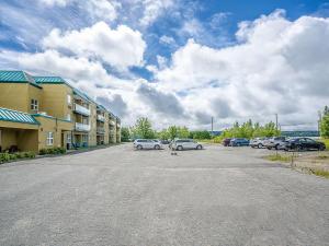 un parking avec des voitures garées à côté d'un bâtiment dans l'établissement Quality Suites, à Sainte-Anne-de-Beaupré