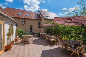 um pátio com mesas, cadeiras e guarda-sóis em Babi Guesthouse - Babi Vendégház em Balatonfüred