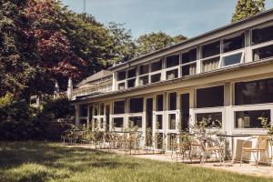 un bâtiment avec des tables et des chaises devant lui dans l'établissement Arnbjerg Pavillonen, à Varde