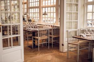 - une salle à manger avec une table, des chaises et des fenêtres dans l'établissement Arnbjerg Pavillonen, à Varde