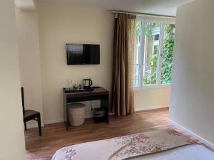 a bedroom with a desk and a television on the wall at Hotel Harder Minerva in Interlaken