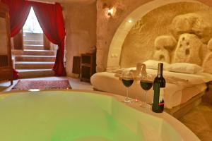 a bathroom with a tub with two glasses of wine at Cappadocia Eagle Cave Inn in Nevşehir