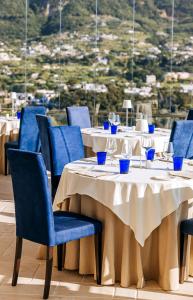 ein Restaurant mit Tischen, blauen Stühlen und Aussicht in der Unterkunft San Montano Resort & Spa in Ischia