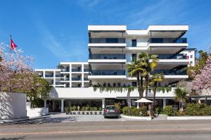 un edificio blanco con un coche aparcado delante de él en Sasso Boretto, Luxury Holiday Apartments en Ascona