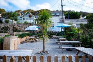 un gruppo di tavoli da picnic con ombrelloni e una palma di Marazion Hotel a Marazion