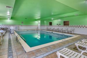 uma grande piscina com cadeiras e mesas brancas em Comfort Inn & Suites em Lawrenceburg