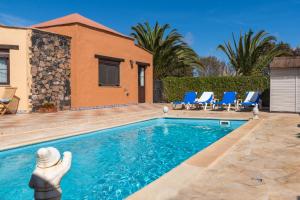 een zwembad met blauwe stoelen en een huis bij Villa Maravilla piscina climatizada in Villaverde