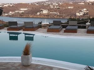 een zwembad met stoelen en uitzicht op het water bij Navy Blue Suites in Ornos