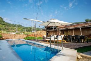 una piscina con sombrilla y sillas junto a una casa en CMYK Stoneyards by the Great Wall en Huairou