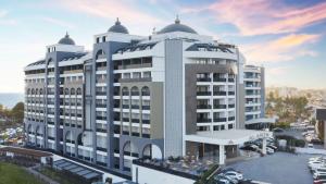 un grand bâtiment blanc avec un parking dans l'établissement Alarcha Hotels & Resort - Ultra All Inc, à Manavgat