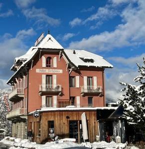 un grand bâtiment avec de la neige au-dessus dans l'établissement Hôtel Terminus, à Orsières